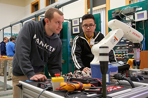 Ranken students working with a Denso robot